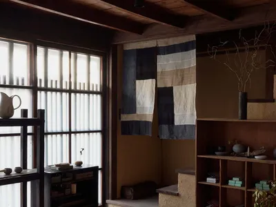 A minimalist residential kitchen featuring wooden elements, stone surfaces, and fabric accents.