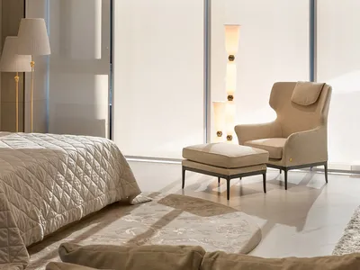 A serene bedroom with a neutral color palette, featuring a bed, armchair, and floor lamp.