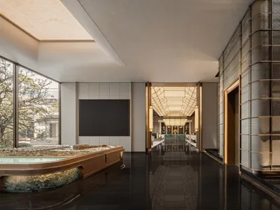 A sleek, modern hotel lobby featuring glass walls and a black marble floor.