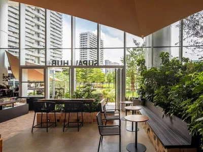 Modern restaurant cafe with green plants, large glass windows, and a concrete floor.