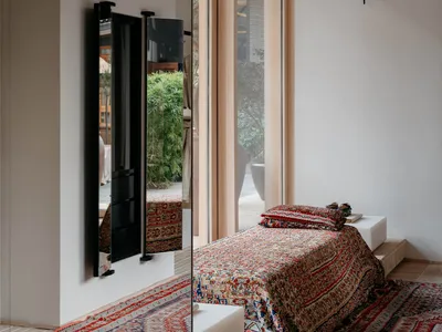 Modern minimalist bedroom featuring a patterned blanket on a raised platform bed.