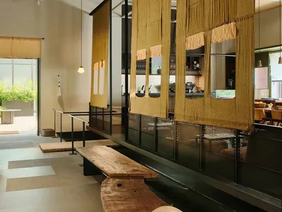 Interior of an industrial-style restaurant featuring wooden and metallic elements and fabric dividers.