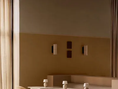 A modern restaurant lounge with fabric seating, concrete tables, and white lampshades.