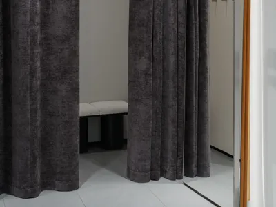 A fashion retail store with velvet curtains and a dressing room.