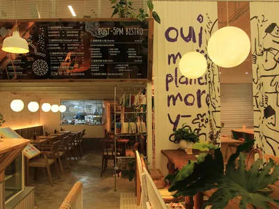 A modern café interior with wooden furniture and hanging lights.