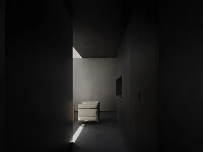 A minimalist living room featuring concrete walls, a single white armchair, and a television.