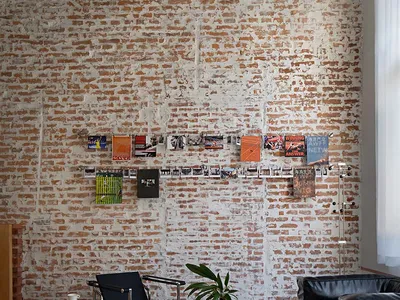 An industrial living room featuring brick and concrete walls, a glass coffee table, and a black leather armchair.
