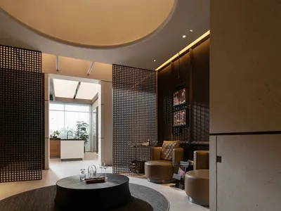 An elegant modern hotel lobby featuring a metal netting and concrete floor, with a circular table and seating area.