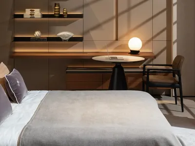 Modern minimalist bedroom featuring glass shelves, a wooden desk, and a metal lamp.