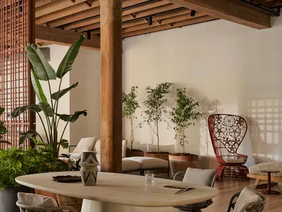 An industrial living room with wood flooring, a wooden beam, and a concrete table.