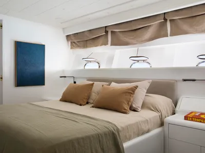 A minimalist bedroom featuring a bed adorned with brown and beige linen pillows and a matching comforter, set against a white