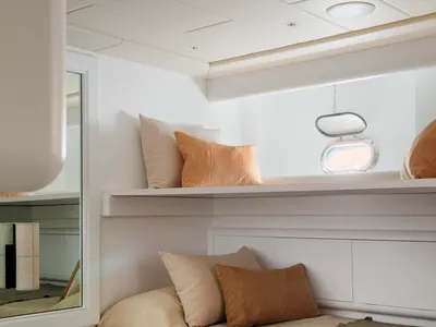 Minimalist bedroom with fabric and wood bedding, pillows, and a window.