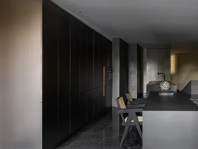 Modern minimalist kitchen with concrete countertops and floor, featuring sleek black cabinets and a central dining table with