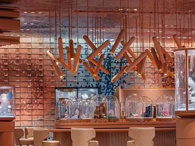 Modern bar interior with wood stools, concrete shelving, and glass dome displays.