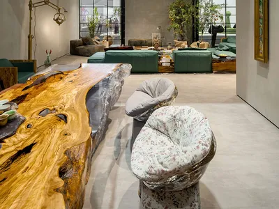 A modern industrial living room featuring a metal structure, green sofas, and a wooden coffee table.