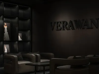 The interior of a retail storefront featuring dark metallic finish leather furniture and a large display of a wedding dress.