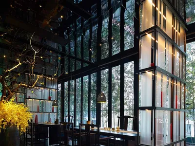 A modern restaurant interior with large glass windows and wooden furniture.