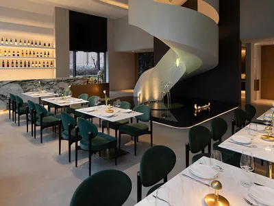 A modern restaurant interior featuring concrete walls and glass elements.