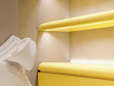 Modern bedroom with yellow plastic headboard and bedding.