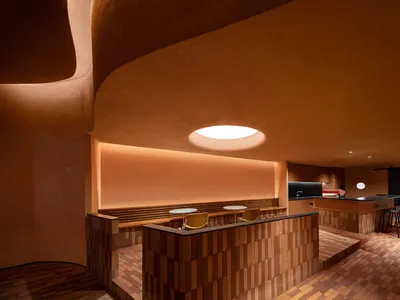 A minimalist restaurant interior with wooden elements and warm lighting.