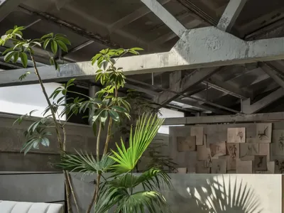 A spacious, industrial-style living room featuring wood furniture, leather accents, and concrete walls.