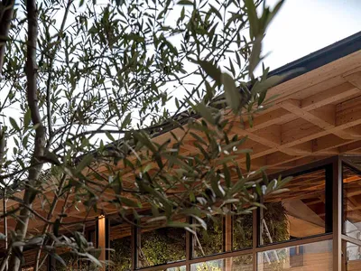 A modern restaurant exterior with large glass walls and wooden furniture