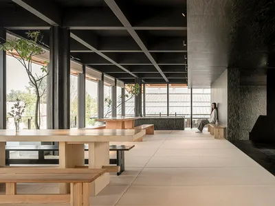 A minimalist restaurant interior with wooden benches and concrete walls.