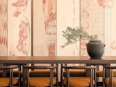 Modern interior design featuring a long wooden dining table with orange fabric chairs and a decorative plant in a ceramic vas