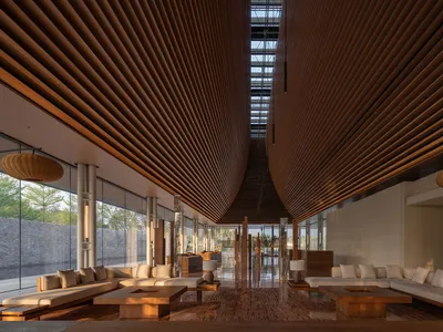 A minimalist hotel lobby featuring wooden interiors and a skylight.