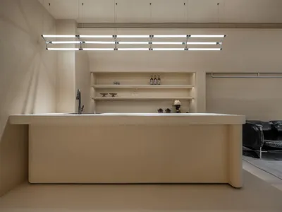 Minimalist kitchen with concrete island, sink, and shelves.
