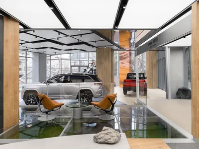 汽車展示間內部，展示一輛銀色休旅車與一輛紅色休旅車，搭配現代座椅與當代設計元素。