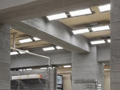 Concrete retail shop interior with clothing racks and signage.