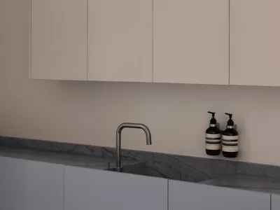Modern kitchen with minimalist design featuring concrete countertops and cabinets.