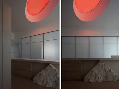 Modern hotel lobby with glass partitions and marble walls illuminated by orange circular lights.