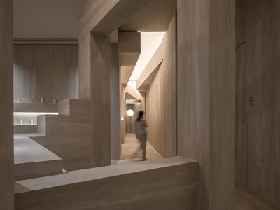 Modern hotel lobby with stone walls and floor, featuring minimalist design elements.