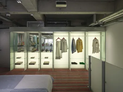 A retail showroom featuring glass shelves and clothing racks.
