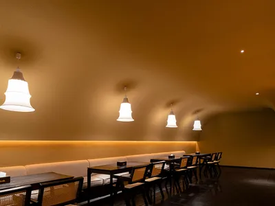 A cozy, modern restaurant interior with wooden furniture and pendant lights.