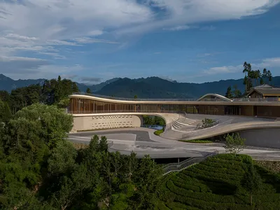 一座現代酒店，擁有混凝土與玻璃外觀，周圍環繞綠意與山景。