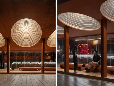 A modern restaurant interior featuring metallic elements and a unique ceiling design.