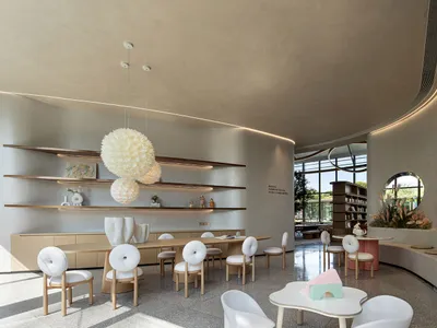 Minimalist design in a contemporary restaurant interior with wooden tables, concrete walls, and glass partitions.