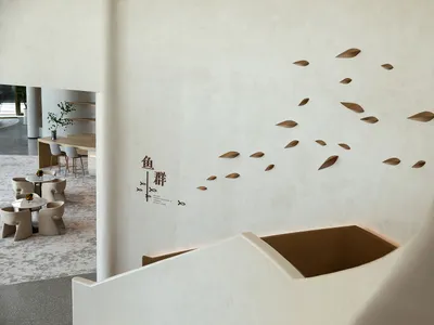 Modern restaurant interior with white concrete walls and a floating staircase.