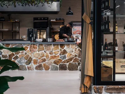 A modern restaurant with a stone countertop and a chef preparing food.