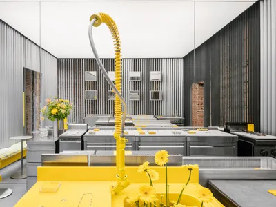 A modern kitchen with yellow tiles, stainless steel appliances, and a white countertop.