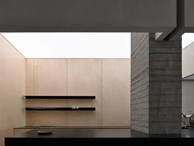 Modern kitchen with minimalist design, featuring wood and concrete materials.