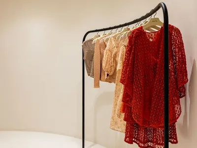 A clothing rack displaying various garments on metal hangers in a fashion store setting.