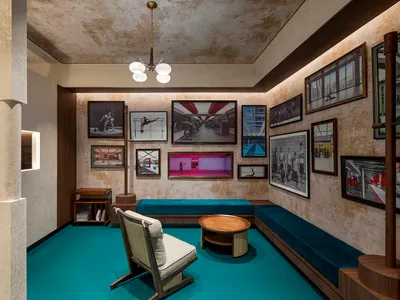 An image depicting a minimalist hotel lobby with concrete walls, wooden furniture, and turquoise accents.