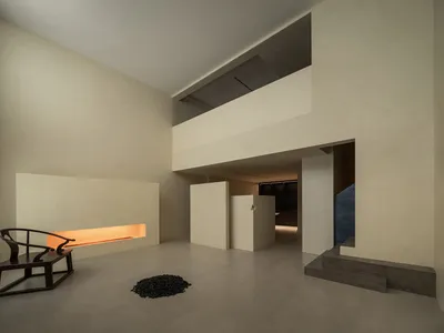 極簡客廳擁有混凝土牆面與地板，由線性嵌入式燈具散發的暖光照亮。