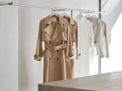 服裝零售展示，展示米色風衣與外套懸掛在金屬衣架上。