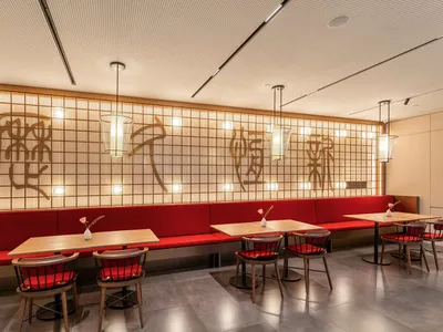Modern, red-themed restaurant interior with wooden furniture and decorative lighting.