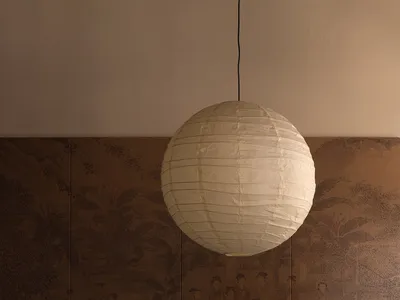 A minimalist living room featuring a white paper lantern hanging from the ceiling, creating a warm and inviting atmosphere.
